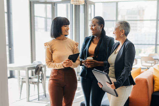 donne d'affari in conversazione di incontro presso la società di agenzia di marketing digitale per l'empowerment, la motivazione e l'innovazione tecnologica. lavoratori aziendali che parlano delle tendenze dei social media in un ufficio informale - multiracial woman foto e immagini stock