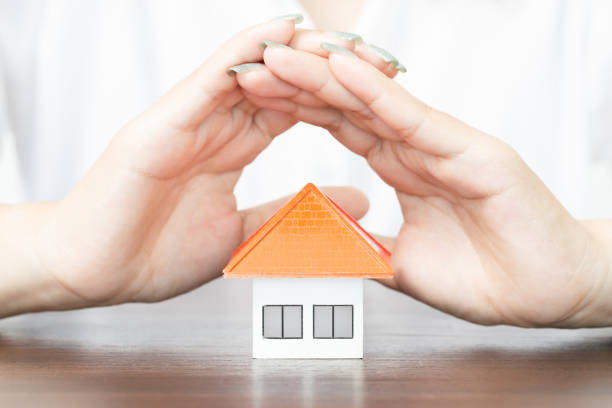 istock young woman use two hand to protect house model. 1425904026