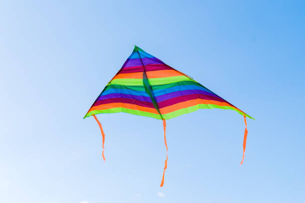 istock Colored striped kite soars in the blue sky 1425912919