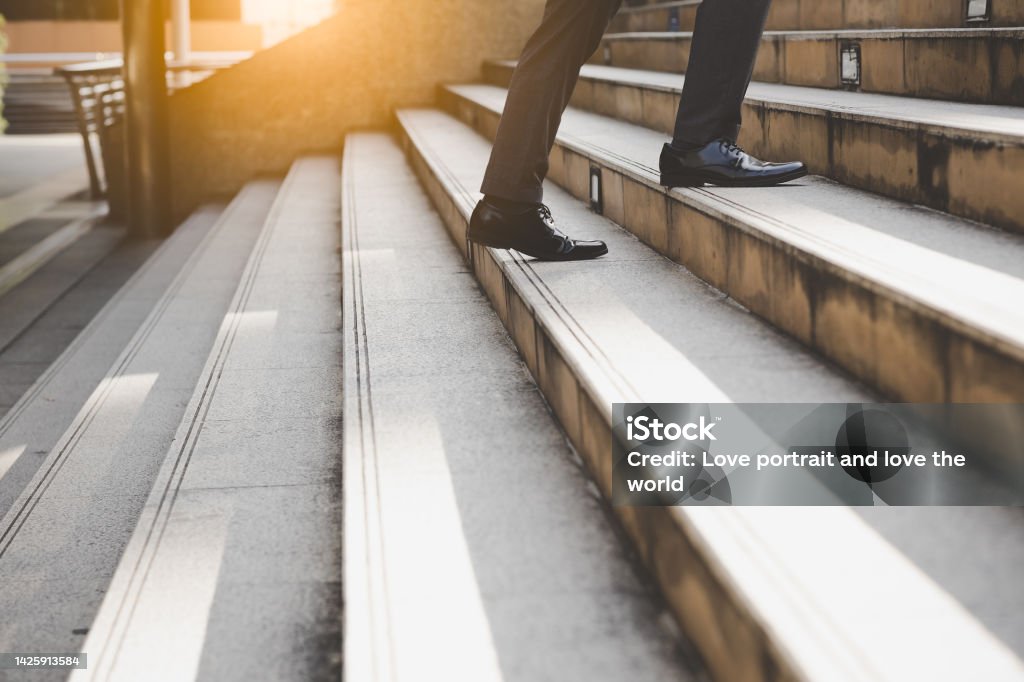 Businessman walking on upstairs taking landscape outdoor shots Unrecognized businessman going to office in the morning in rush hour selective focus Business White collar worker and leadership concept Staircase Stock Photo