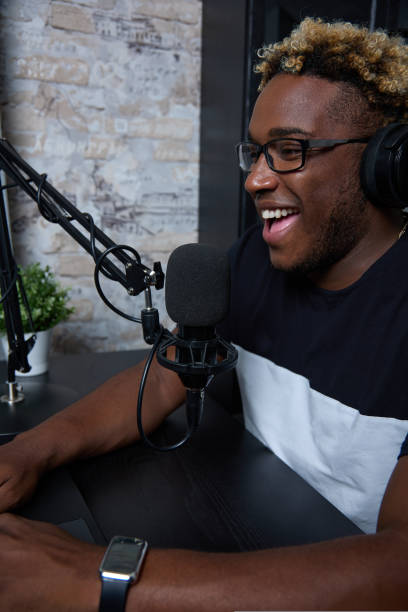 istock Joyful black radio presenter in a modern loft-style studio hosts the program 1425925460