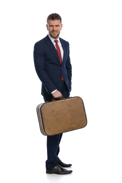 attractive businessman feeling disgustedly surprised with what he sees and holding a luggage, going on a trip