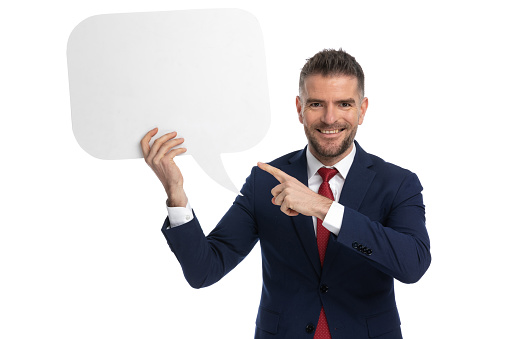 young businessman pointing at the speech bubble he's holding and smiling at the camera