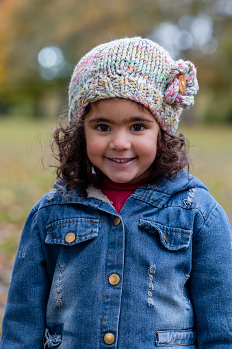 A young girl standing outdoors in a public park in Hexham, North East England. She is looking at the camera and smiling.