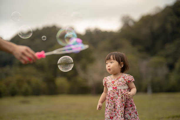 Asian Chinese baby girl excited playing soap bubble stock photo