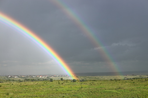 Bright double rainbow with dark rain clouds in the background in Rivne, Rivne Oblast, Ukraine
