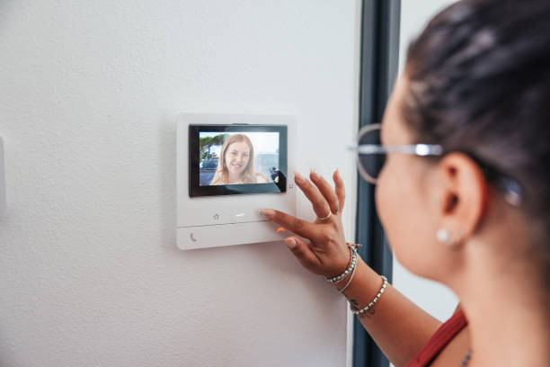 Friends at the door, woman picking up video intercom stock photo