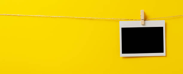 istock An empty photo is hanging on a rope with a clothespin. A design element. Yellow background. Copy space. 1425938171