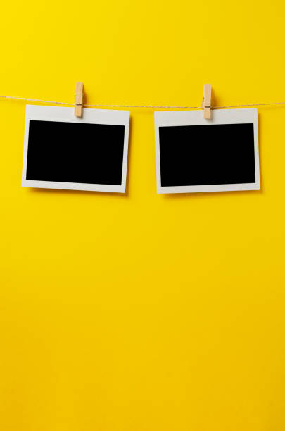 istock Empty photos hang on a rope with clothespins. A design element. Yellow background. Copy space. 1425938173