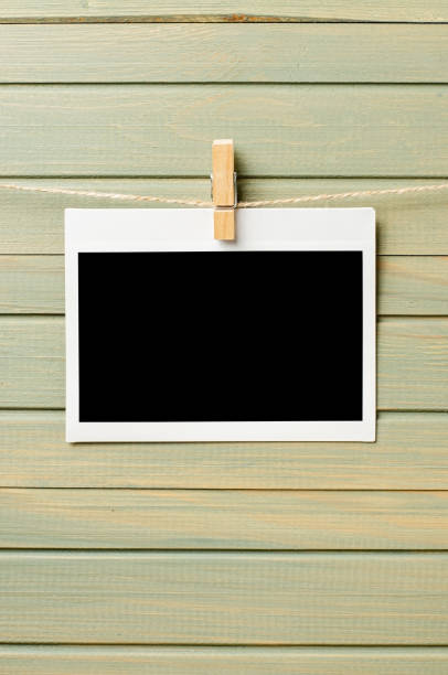 istock An empty photo is hanging on a rope. A design element. Wooden background. Copy space. 1425938175