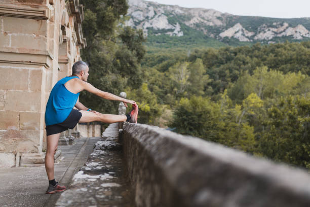 Man runner stretching leg and feet and preparing for trail running outdoors. stock photo