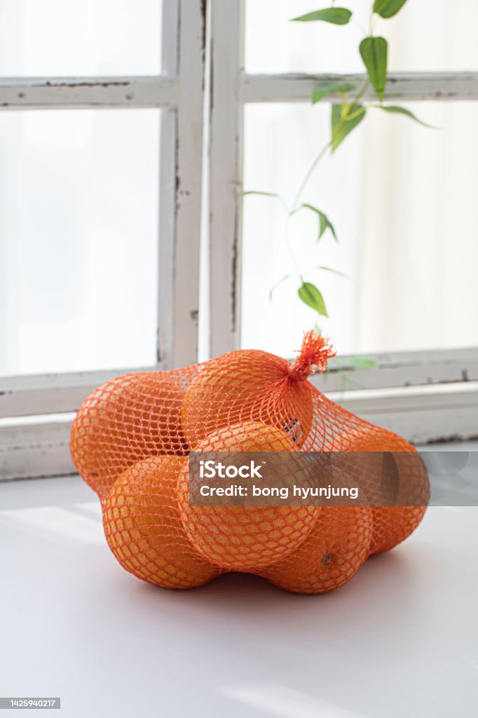 Fresh Oranges in Plastic Mesh Sack on White Background Bag Stock Photo