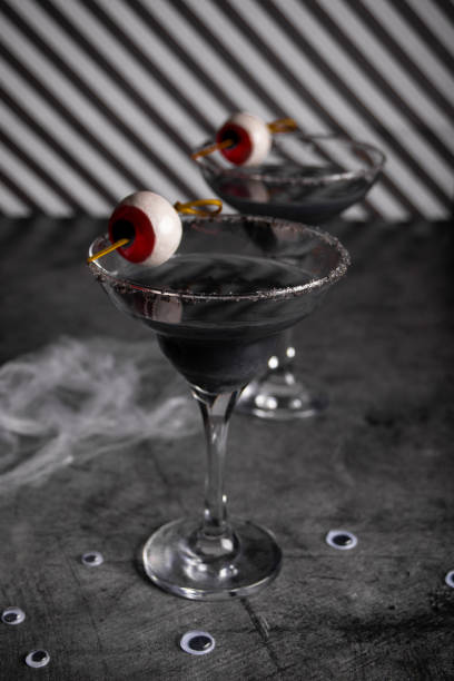 Halloween black cocktail in glasses with candy eyeball. Party festive celebrate concept. stock photo