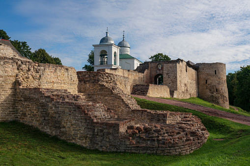View of the wall of the Izborsk fortress, the Nikolsky Gate and St. Nicholas (Nikolsky) Cathedral (XIV-XVII century) on a sunny summer day, Izborsk, Pskov region, Russia