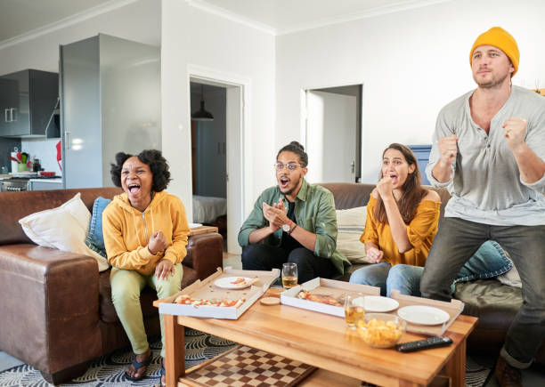 istock Cheering friends watching sports on tv while eating pizza 1425945451