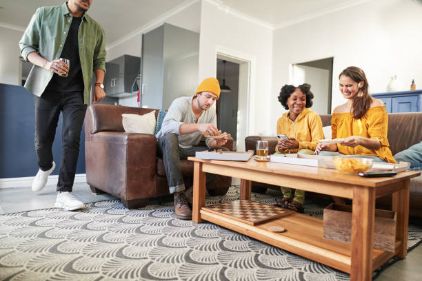 istock Laughing young friends eating pizza around a coffee table 1425945464