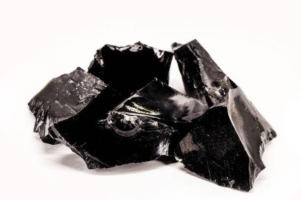 istock Black Obsidian, black and crystalline ore on isolated white background. Black colored stone, therapeutic, used in meditation. 1425945472