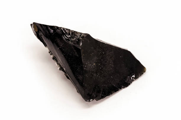 istock Black Obsidian, black and crystalline ore on isolated white background. Black colored stone, therapeutic, used in meditation. 1425945476