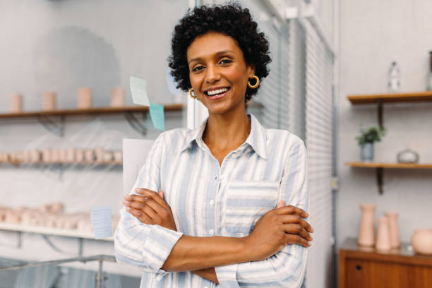 успешный владелец малого бизнеса улыбается в камеру в офисе - happiness african ethnicity cheerful businesswoman стоковые фото и изображения