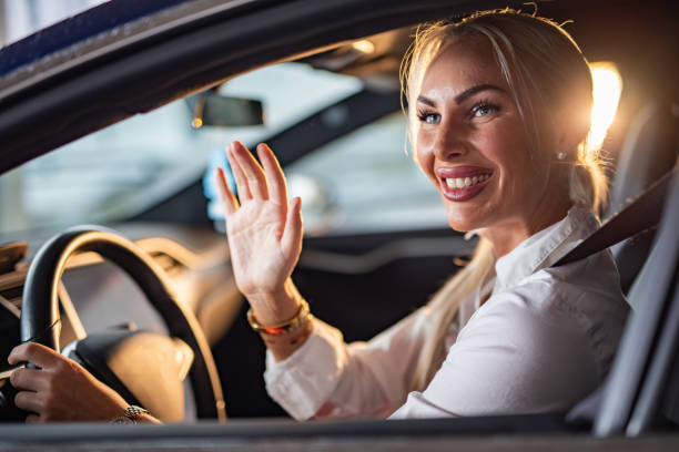 istock Woman waveing to someone while driving a car 1425955615