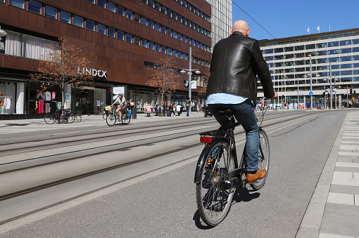 Stockholm, Sweden - May 12, 2021: Rear view of a male cyclist rides on the bike path on Klarabergsgatan street at Sergels torg square.