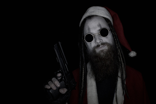 Bad Santa Claus with gun over dark background