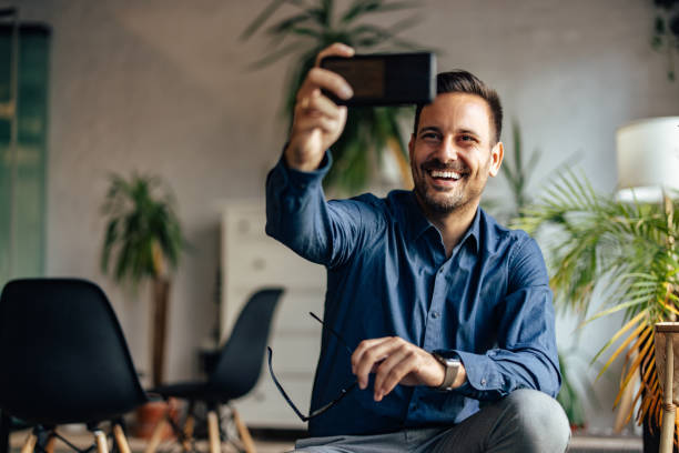 istock Smiling businessman taking a selfie with his mobile phone. 1425957863