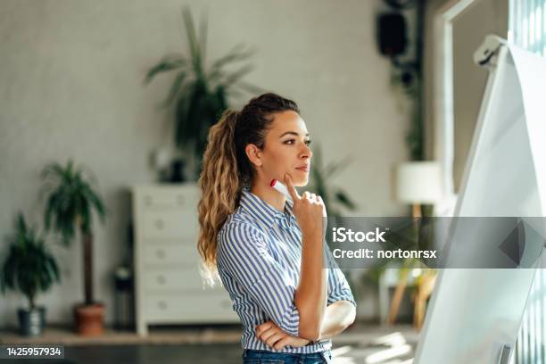 Concentrated Girl Looking At The White Board Holding A Marker Stock Photo - Download Image Now