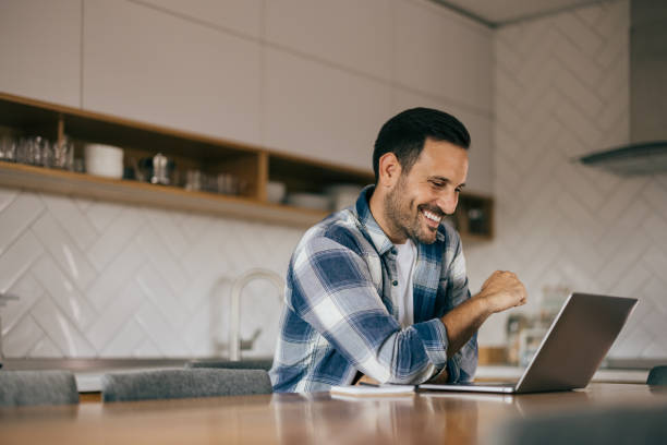 istock Happy adult man using a laptop at home, working something online. 1425958183