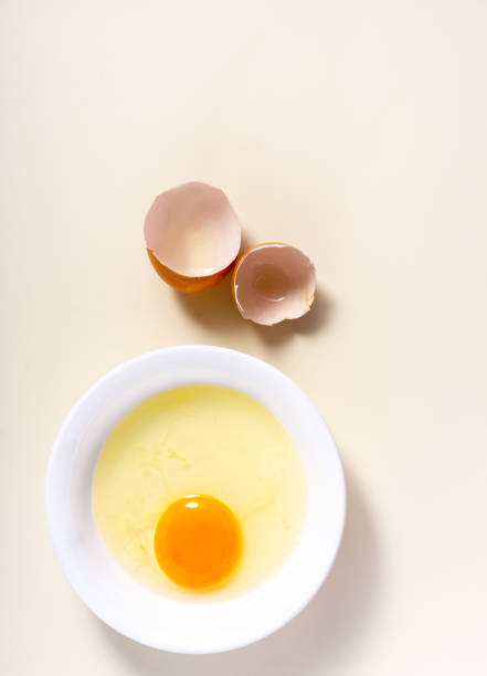 istock Raw eggs and egg shell in a glass bowl on the table. Top View. Broken White Background. 1425958661