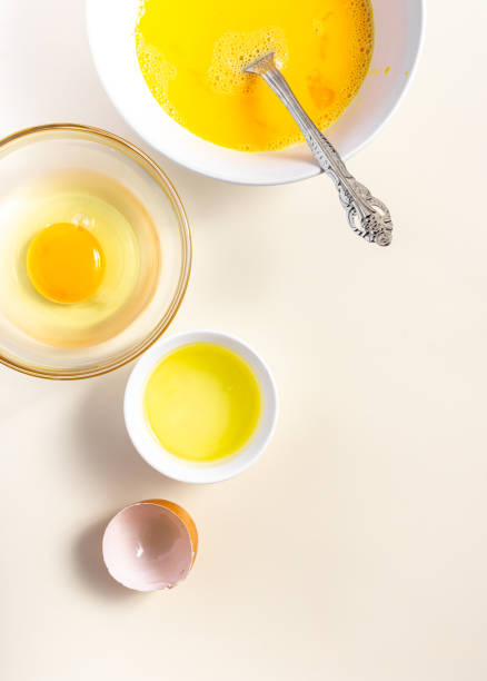 istock Raw eggs in a glass and white bowl on the table. Top View. Broken White Background. Place for Text. 1425958756