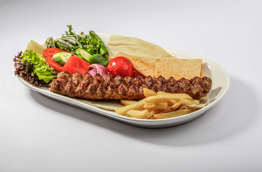MEAT kebab platter with salad, fries, and pita bread served in dish side view of arab food