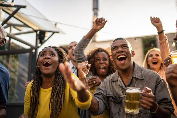 Sports fans watching a match and celebrating at a bar rooftop Sports fans watching a match and celebrating at a bar rooftop black people bar stock pictures, royalty-free photos & images