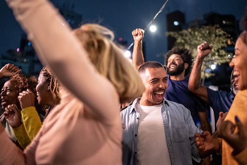 Sports fans watching a match and celebrating at a bar rooftop