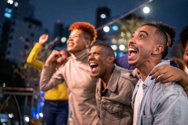 Sports fans watching a match and celebrating at a bar rooftop Sports fans watching a match and celebrating at a bar rooftop black people bar stock pictures, royalty-free photos & images