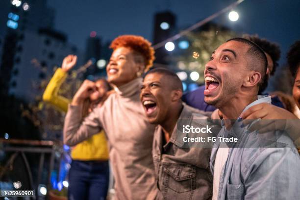 Sports Fans Watching A Match And Celebrating At A Bar Rooftop Stock Photo - Download Image Now