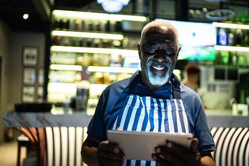 Portrait of a senior man using digital tablet working in a bar