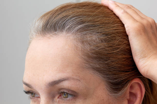 cabeza de mujer con la mano sobre el pelo gris - women middle aging process covering fotografías e imágenes de stock
