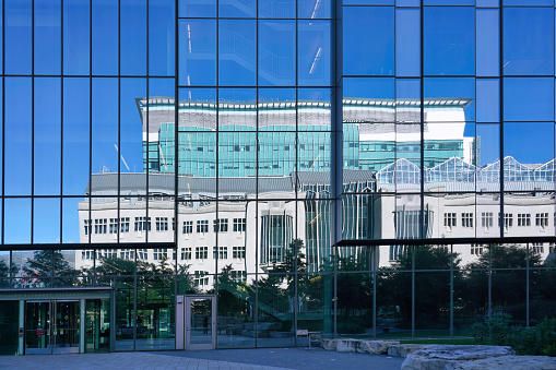 Chicago, USA - September 1, 2022:   The  University of Chicago's Pritzker Medical School reflected in the mirrored facade of an adjacent medical research building.