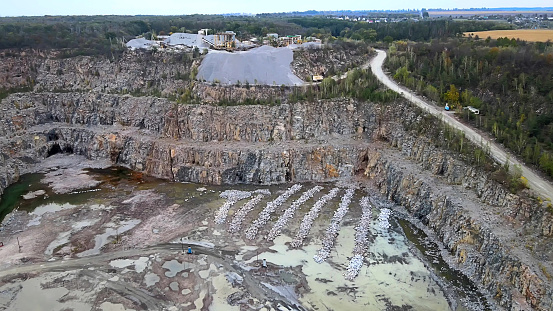 Aerial drone view of career in Europe at summer sunset, crushed stone quarry, beautiful nature round, some excavators, diggers inside