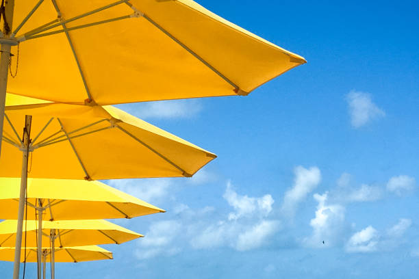 Nevis; June 2017; Yellow beach umbrellas set against the blue sky with clouds in the distance
