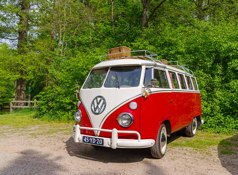 1950s Volkswagen Bus or Kombi Samba or Sunroof Deluxe classic camper van car. The Samba was the most luxurious Volkswagen Transporter first generation T1. The car is driving through the country.