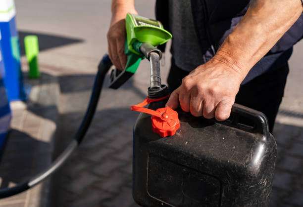 um homem enche combustível em uma lata de plástico em um posto de gasolina - gas can - fotografias e filmes do acervo