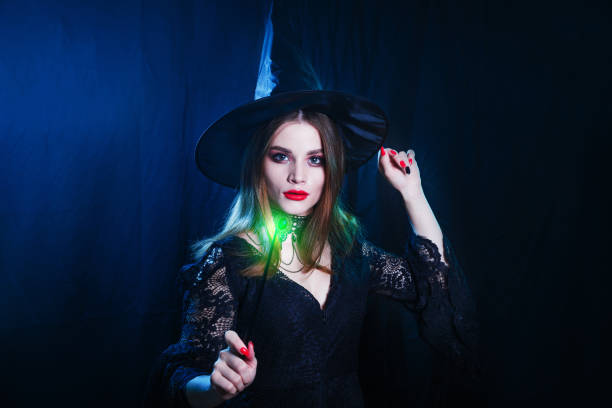 istock Beautiful witch with magic stick on dark background. Halloween witch concept 1425970475