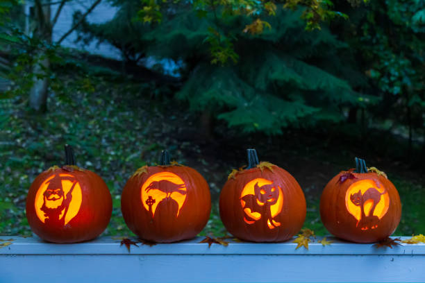 Four Halloween Jack O'Lantern pumpkins glowing in the dark