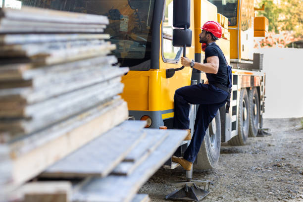 Young Building Worker is Entering the Cabin of a Large Construction Machine at the Building Site.