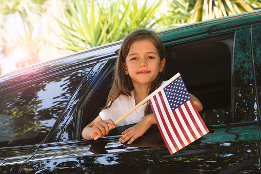 Girl holding American flag in the car.