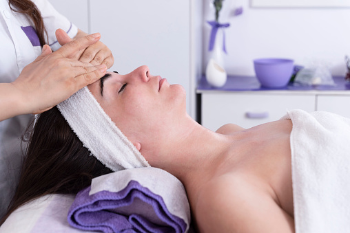 Esthetician performing professional facial massage on woman's face in spa clinic. Anti-aging massage with face lift. Professional lymphatic drainage massage in the beauty salon
