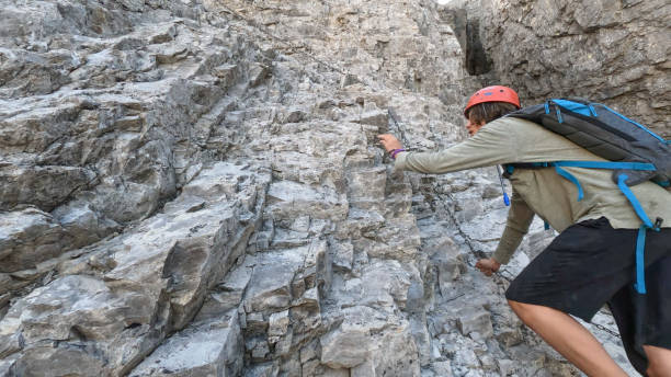 istock Teen boy scrambles up rock face using chain 1425992229