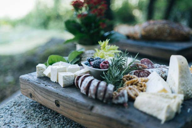 차가운 고기와 치즈를 야외에서 테이블에 올려 놓은 보드 - meat and alternatives dinner lunch picnic 뉴스 사진 이미지